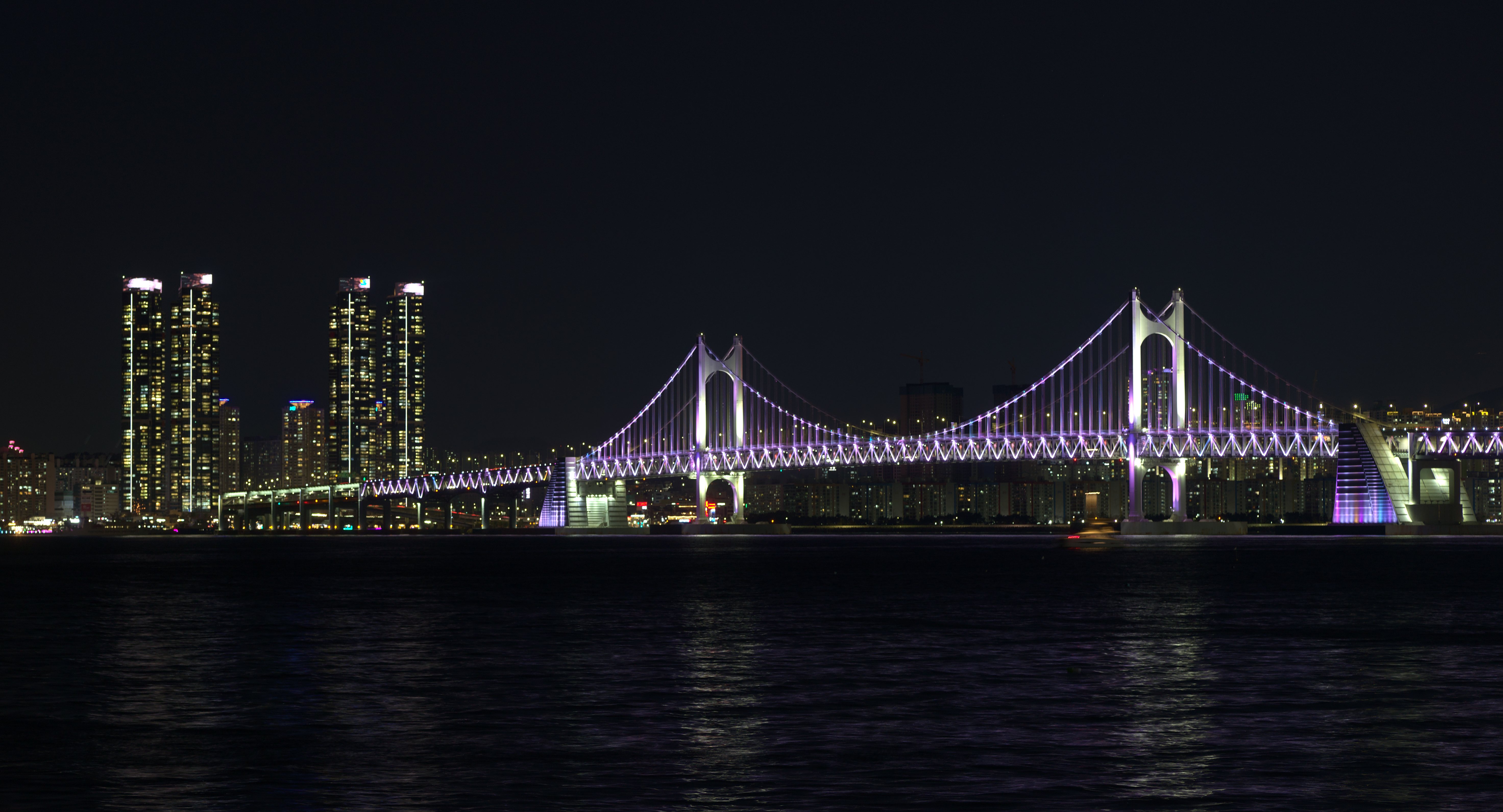 Korean coastal skyline and illuminated bridge at night